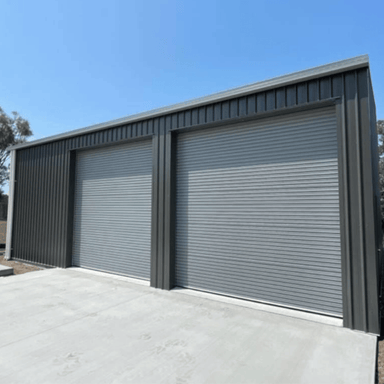 Two garage doors on a building with a clear blue sky.
