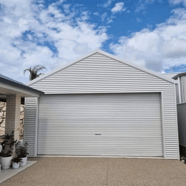 White garage door on a house with a blue sky and clouds in the background