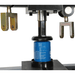 Blue oil filter being crushed by a machine with metallic components on a white background