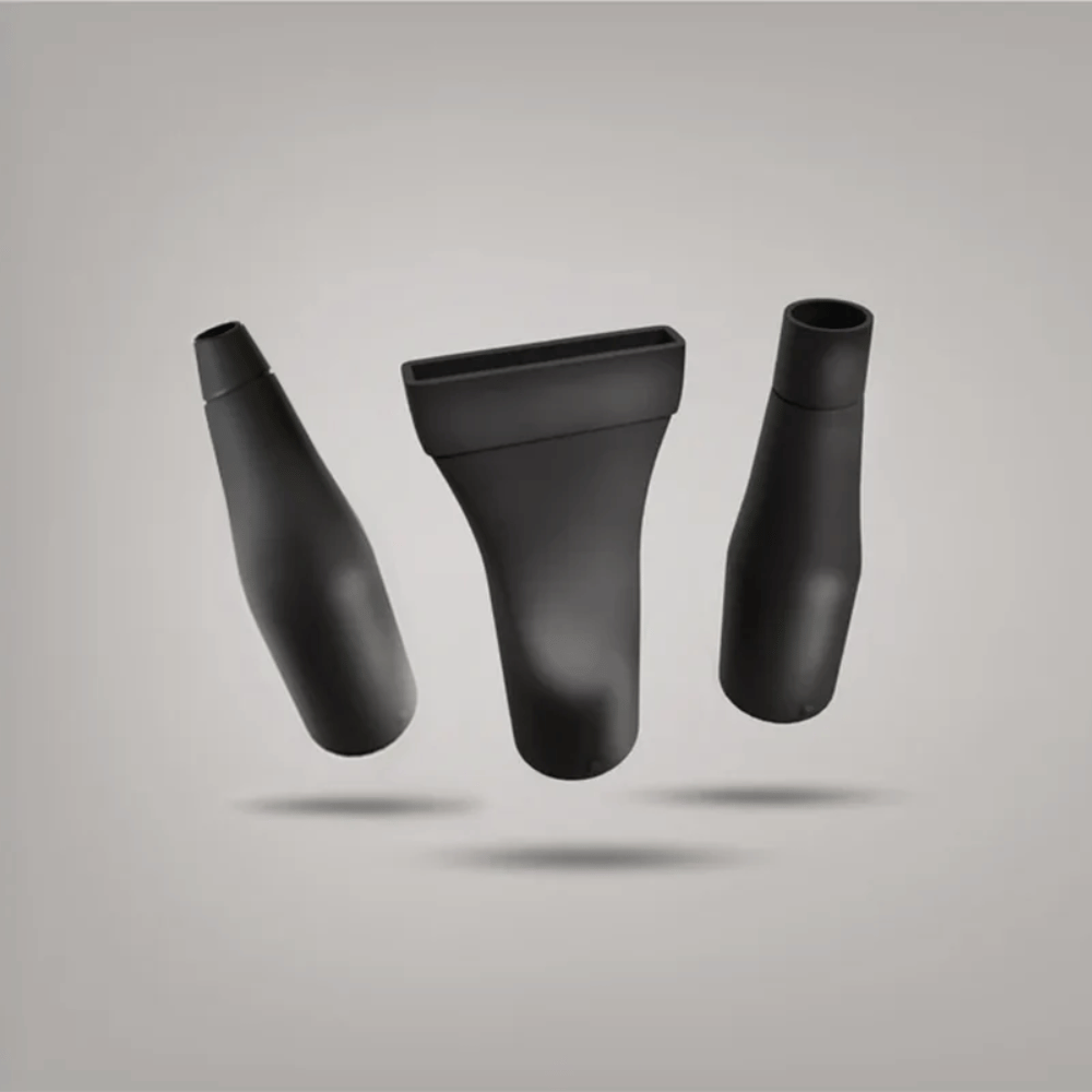 Three black plastic blowR nozzles on a gray background