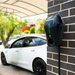 Ocular IQ EV charger installed on a brick wall with a white electric car parked behind